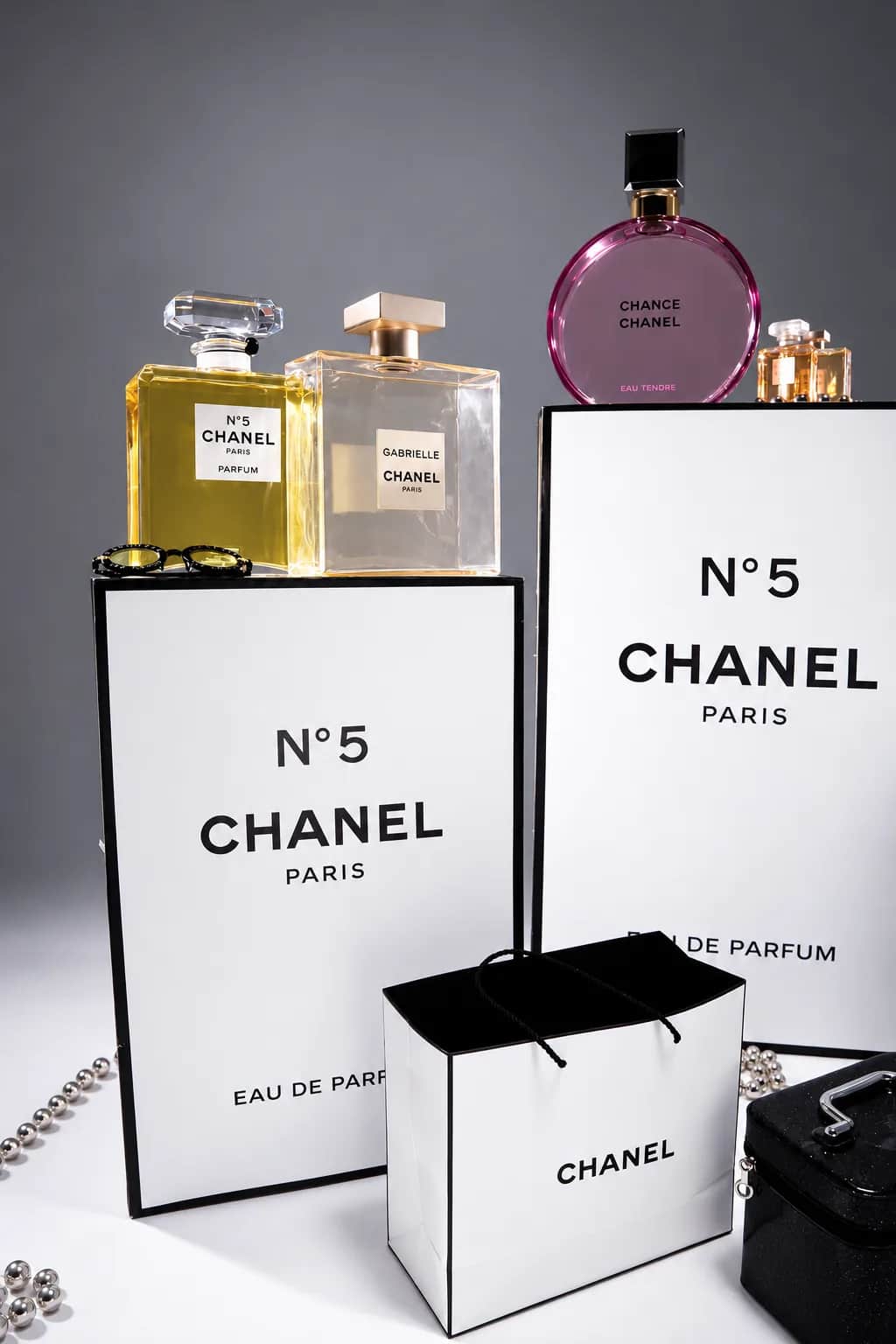 Флаконы на белых подиумах CHANEL, белая сумка и металлические бусы