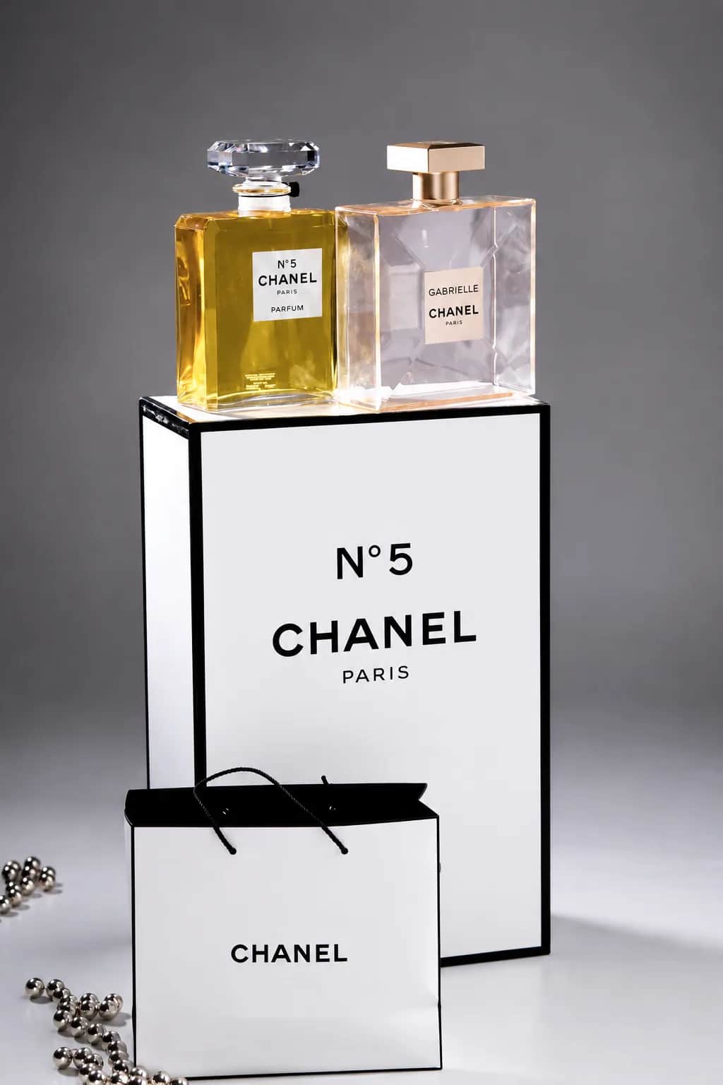 Два флакона на белом подиуме CHANEL N°5 и сумка на переднем плане